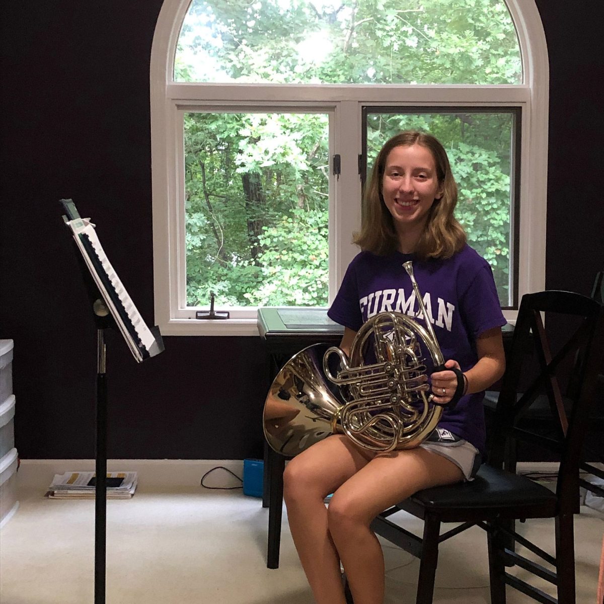 Jordan Hembree (‘23) poses with her French horn and music stand in her at-home practice area.